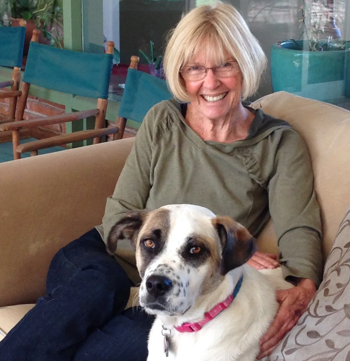 A woman with dog sitting on couch smiling