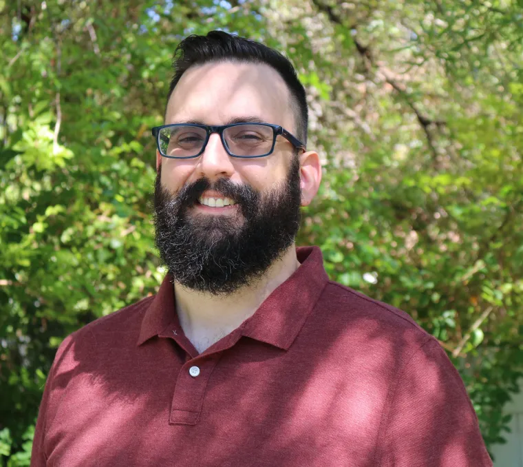 Photo of man with beard and glasses smiling at camera