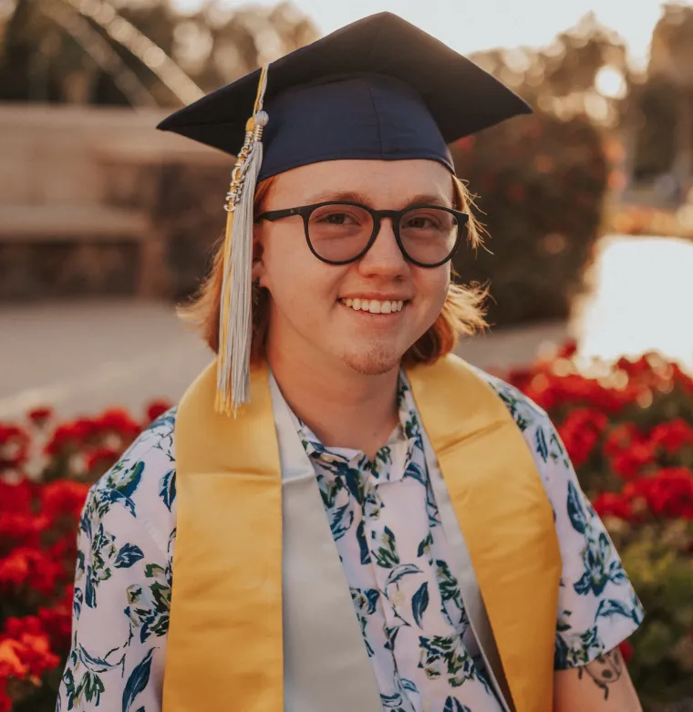 Headshot of Austin smiling at the camera wearing graduation cap