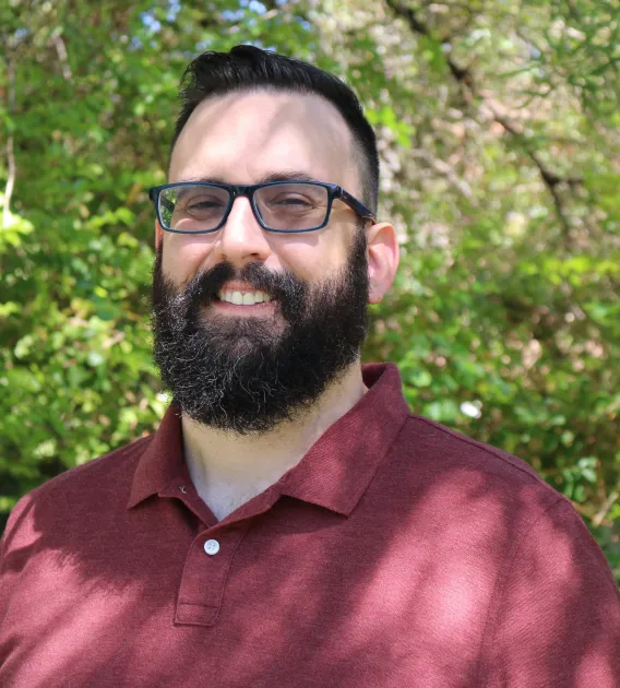 Photo of man with beard and glasses smiling at camera