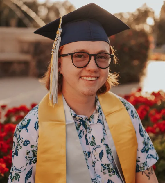 Headshot of Austin smiling at the camera wearing graduation cap